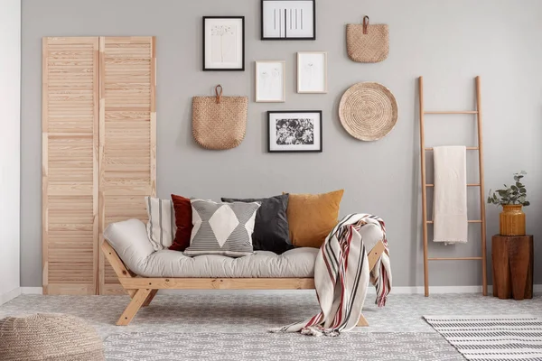 Aksesoris kayu dan wicker di interior ruang tamu Skandinavia dengan sofa futon dengan bantal — Stok Foto