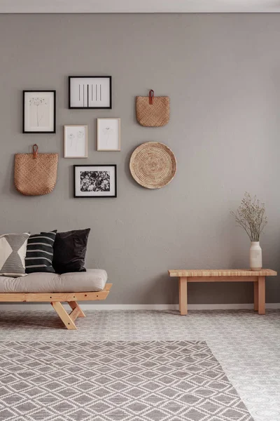 Fleurs sèches dans un vase blanc sur une petite table en bois derrière un confortable canapé futon avec oreillers — Photo