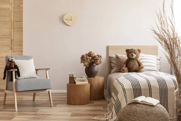 Flowers in brown vase on wooden nightstand table next to single bed with stripped bedding with teddy bear — Stock Photo, Image