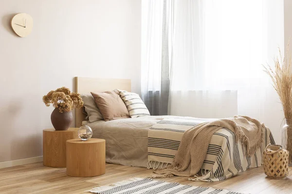 Quarto de hotel brilhante e natural interior com cama de solteiro e mesa de cabeceira de madeira com flores — Fotografia de Stock