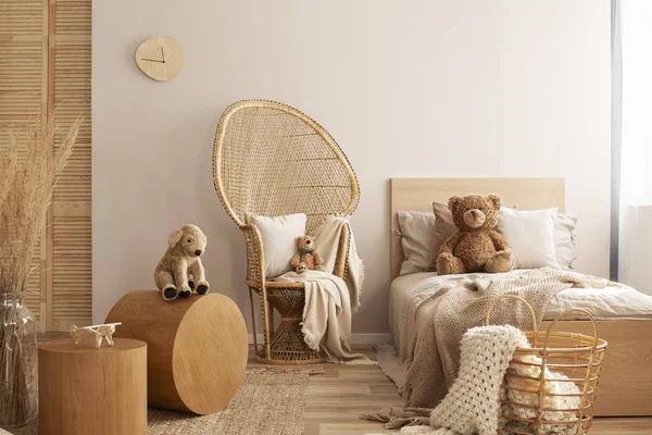 Плетеный стул павлина с подушкой, креслом и игрушкой в бежевом и деревянном интерьере детской спальни — стоковое фото