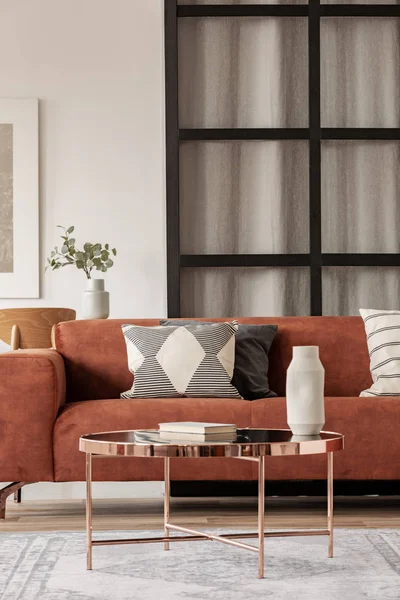Стильний коричневий кутовий диван з візерунчастими подушками в елегантному інтер'єрі вітальні з муліне стіною — стокове фото