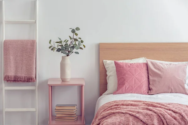 Almohada rosa pastel y manta en una cama de madera con ropa de cama blanca en el interior del dormitorio escandinavo — Foto de Stock