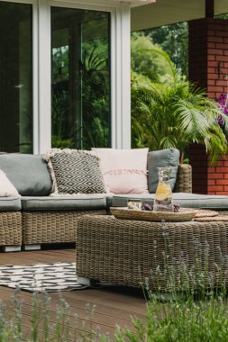 Hasır sehpada içecekler rahat kanepeli şirin bir teras.