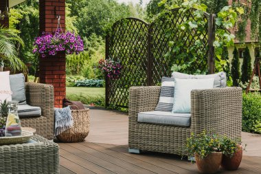 Trendy banliyö ev ahşap terasta yastık ile rahat hasır koltuk