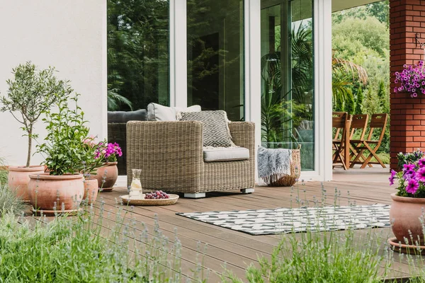 Poltrona de vime confortável com travesseiros no terraço de madeira da casa suburbana na moda — Fotografia de Stock