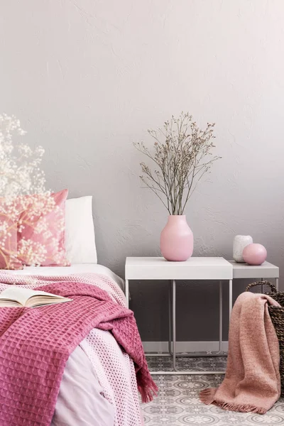 Torra blommor i pastell rosa vas på enkla nattduksbord bredvid sängen — Stockfoto