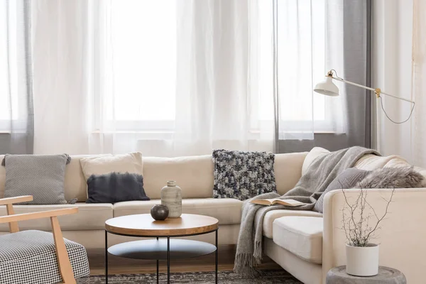 Béžová pohodlná pohovka s šedými polštáři v elegantním interiéru obývacího pokoje s bílou zdí — Stock fotografie