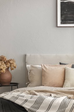 İskandinav yatak odası iç kral yatak yanında metal komandite üzerinde çanak çömlek vazo kahverengi çiçekler