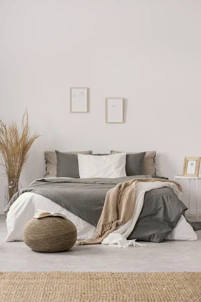 Couvertures blanches et beiges sur couette grise sur lit confortable dans un intérieur lumineux de chambre — Photo