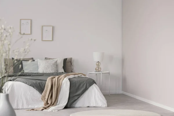 White and beige blankets on grey duvet on comfortable bed in bright bedroom interior — Stock Photo, Image