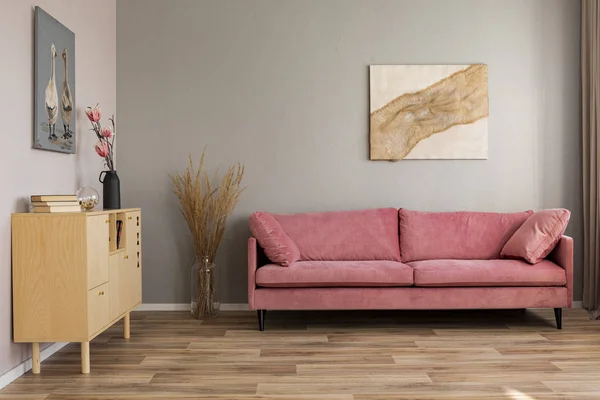 Flores em vasos em cômoda de madeira na sala de estar contemporânea interior com sofá rosa pastel — Fotografia de Stock