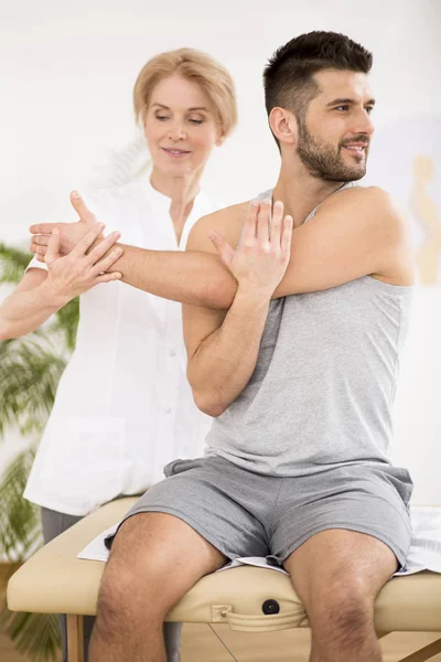 Handsome young man during physiotherapy session with professional doctor — Stock Photo, Image