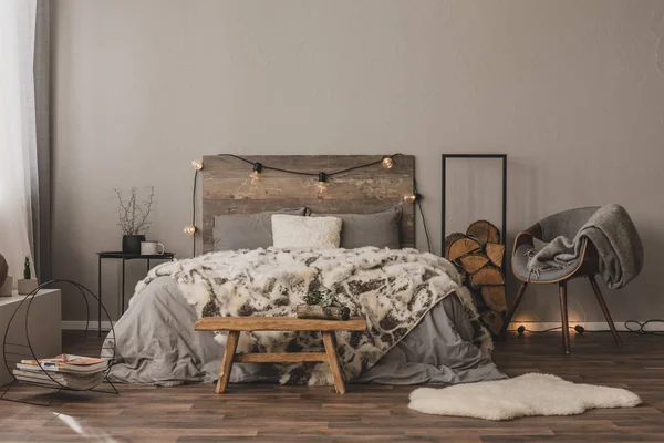 Пространство для копирования на пустой серой стене стильного интерьера спальни с деревянными акцентами и двуспальной кроватью — стоковое фото