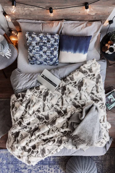 Bovenaanzicht van ongemaakt bed met grijs beddengoed, warme Fury deken en laptop — Stockfoto