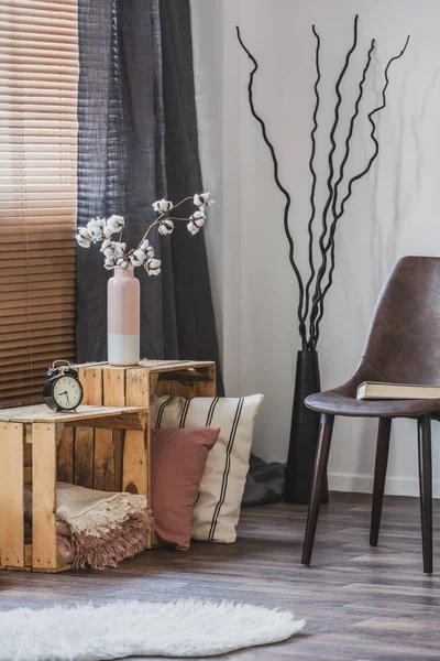 Prawdziwe zdjęcie rustykalnego wnętrza salonu z drewnianymi skrzyniami, książka na skórzanym fotelu i futro dywan — Zdjęcie stockowe