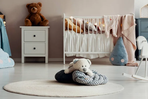 White teddy bear on dotted pillow on the floor of trendy baby bedroom — Stock Photo, Image