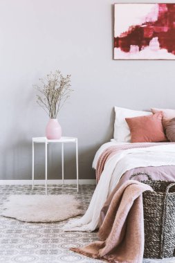Vazoda hasır sepet ve çiçekler ile pembe ve gri yatak odası iç dikey görünümü