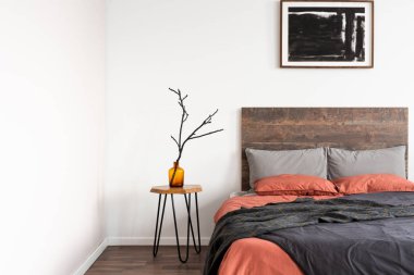 Turuncu ve gri yataklı kral yatak ahşap komanditmasa yuvası üzerinde cam vazo kuru dal