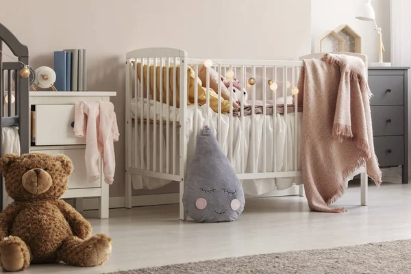 Osito de peluche marrón en el suelo de madera del escandinavo dormitorio de bebé interior con mesita de noche blanca y cunas —  Fotos de Stock