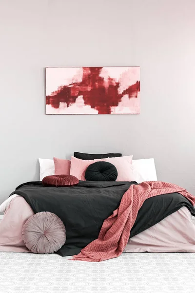 ピンクと黒の寝具とキングサイズベッドの上に抽象的なアマランとパステルピンクの絵 — ストック写真