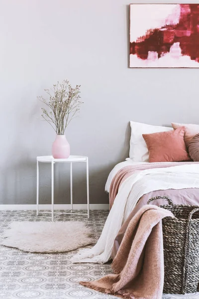 Vertical view of pink and grey bedroom interior with wicker basket and flowers in vase — Stock Photo, Image