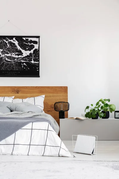 Copy space on white wall with black map in modern bedroom with king size bed with wooden headboard — Stock Photo, Image