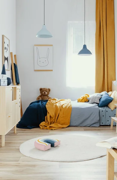 Ведмедик на одне дерев'яне ліжко в синьому і помаранчевому інтер'єрі спальні — стокове фото