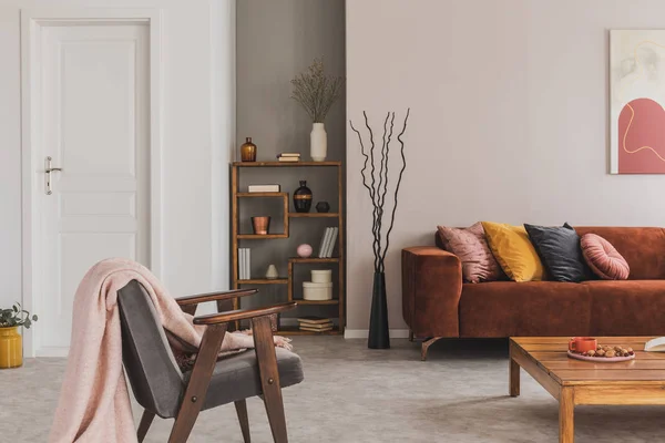Сіре вінтажне крісло з пастельно-рожевою ковдрою в елегантній і атмосферній квартирі — стокове фото