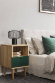 Béžová a smaragdová ložnice s moderním světlometem na dřevěném stolku