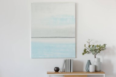 Vazo ve kitaplarda çiçekler ile konsol masa ile boş beyaz duvara pastel mavi ve beyaz soyut yağlıboya