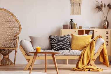 Yastıklı modern İskandinav settee yanında çarpıcı hasır tavus kuşu sandalye