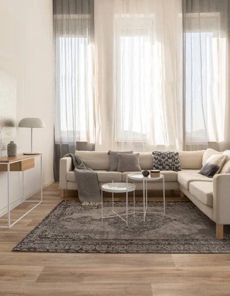 Cómodo sofá de esquina beige con almohadas grises en el elegante salón interior con pared blanca —  Fotos de Stock