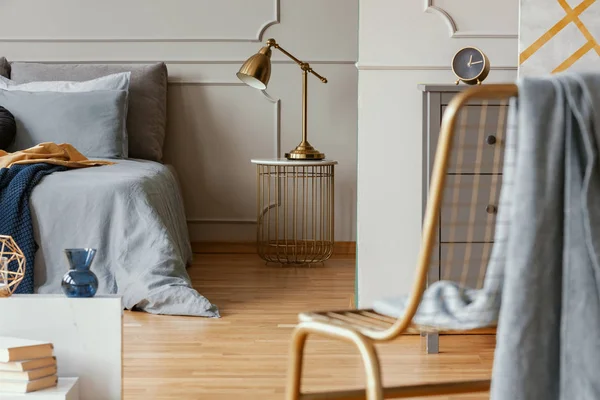Современный интерьер спальни с серым комодом и золотым стулом — стоковое фото