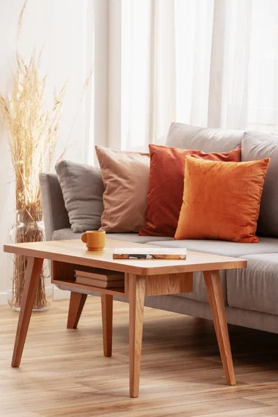 Retro wooden coffee table in front of grey couch in classy living room interior