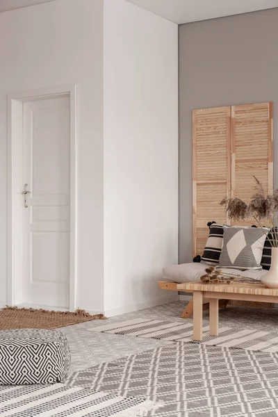 Белый и яркий вход в натуральную гостиную с ковриками, подушками и деревянным экраном — стоковое фото