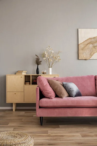 Virágok vázák a fából készült komteron a kortárs nappali belsejében pasztell rózsaszín kanapé — Stock Fotó