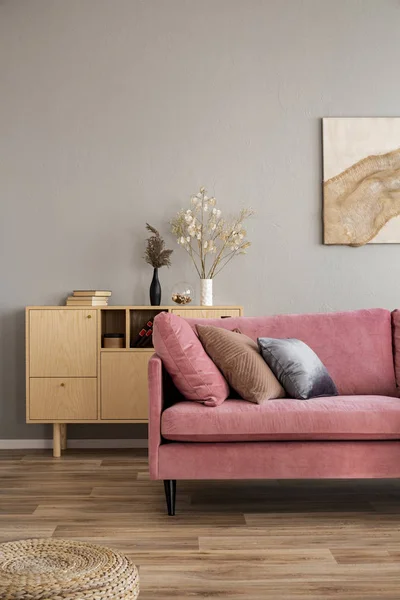 Blumen in Vasen auf Holzkommode im zeitgenössischen Wohnzimmerinterieur mit pastellrosa Sofa — Stockfoto