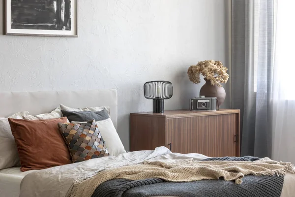 Vintage wooden cupboard next to king size bed with pillows and blanket in trendy bedroom interior — Stock Photo, Image