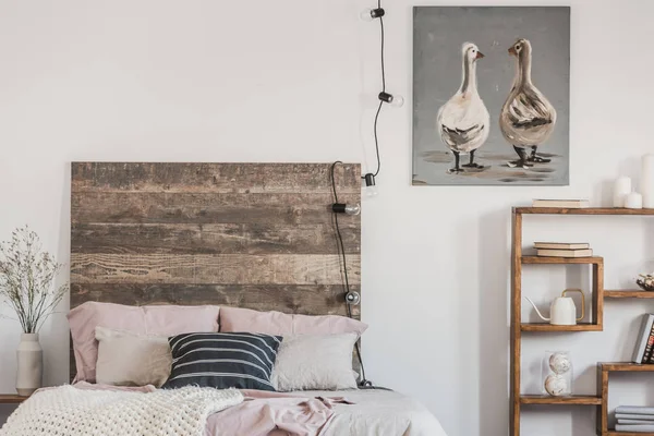 Śliczne kaczki na szary obraz olejny w białym rustykalnym sypialni wnętrze z fantazyjną półkę i łóżko z drewnianym zagarowaniem — Zdjęcie stockowe