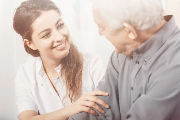 Vacker volontär leende på Senior man på sjukhem — Stockfoto