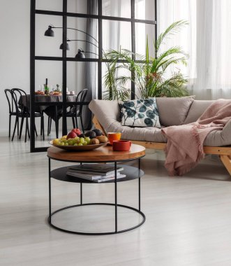 İskandinav şiltesinin önündeki küçük sehpanın üzerinde desenli yastık ve patel pembe battaniye var.