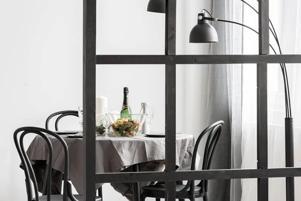 Insalata e vino in sala da pranzo tavolo con tovaglia grigia e sedie in legno nero — Foto Stock