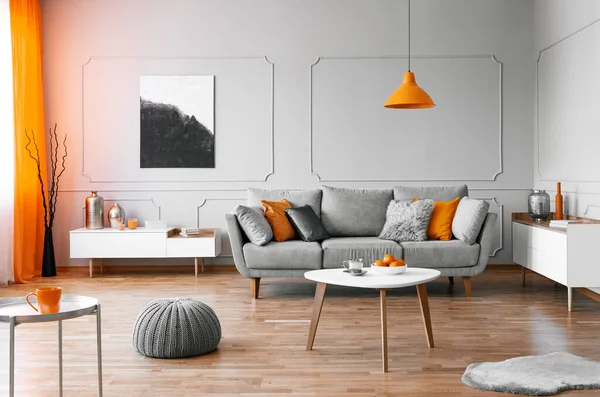 Stilfuldt sofabord med kinck knacks foran elegant sofa med puder - Stock-foto