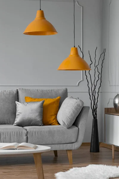 Pomerančová lampa nad šedou skandinávskou pohovkou v moderním interiéru — Stock fotografie