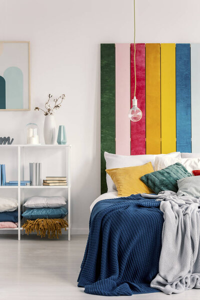Vertical view of bed with pillows and blanket next to book shelf with books and vases