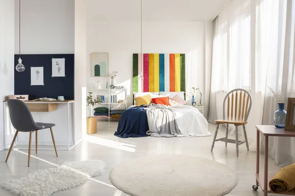 의자와 무지개 빛깔 침대위가 있는 사무실 이 있는 흰 침실 내부 — 스톡 사진