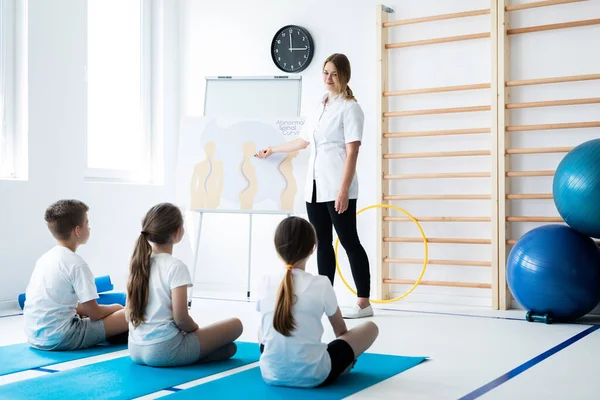 Jonge Fysiotherapeut Praat Met Kinderen Slechte Houdingen — Stockfoto