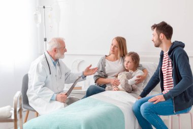 Kıdemli doktor küçük kızın ailesiyle ameliyat hakkında konuşuyor.