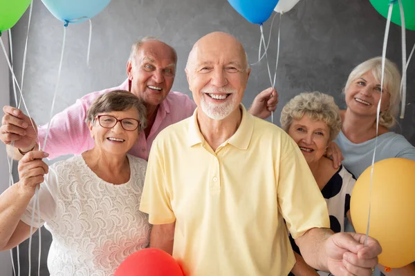 Sorrindo Amigos Seniores Com Balões Coloridos Interior Escuro Com Parede — Fotografia de Stock